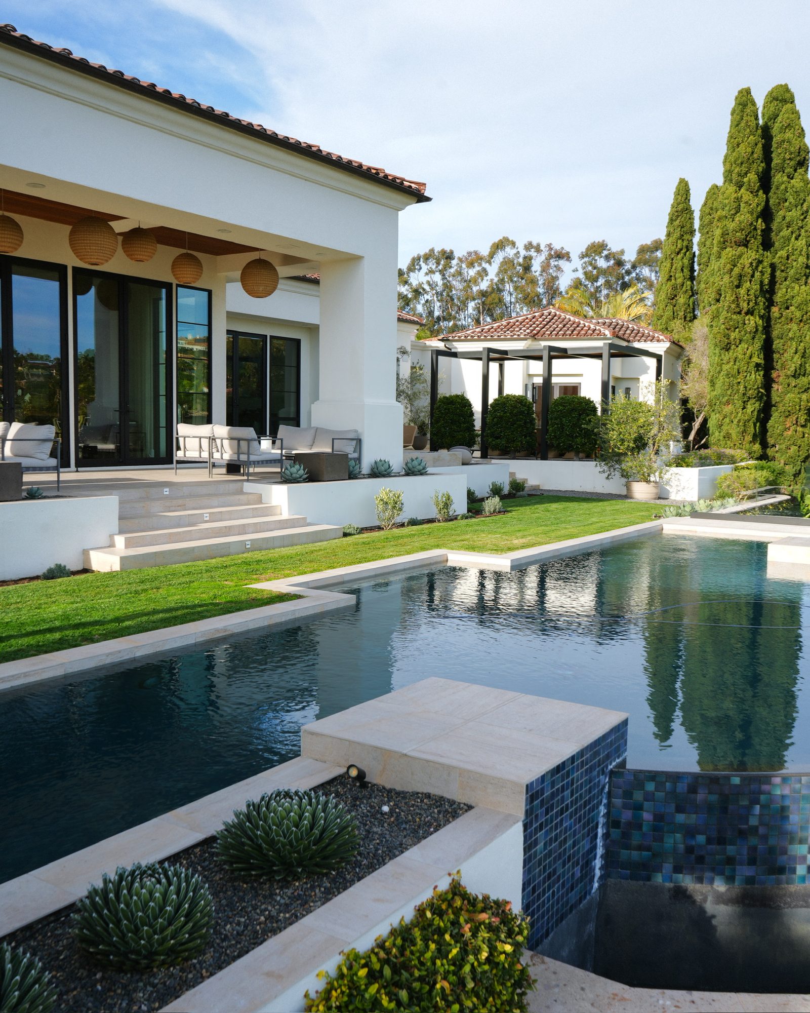 Infinity-edge pool beside the estate with the covered patios beyond