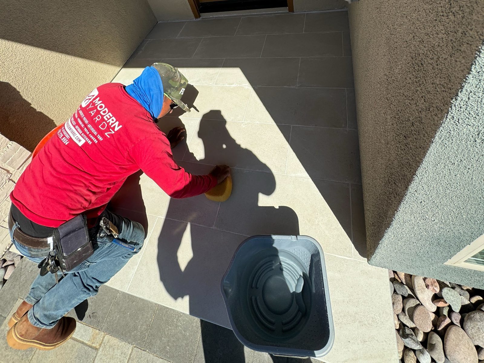 Abshire Brothers Lawn & Landscape installer polishing a porcelain paver entry landing in Rayne