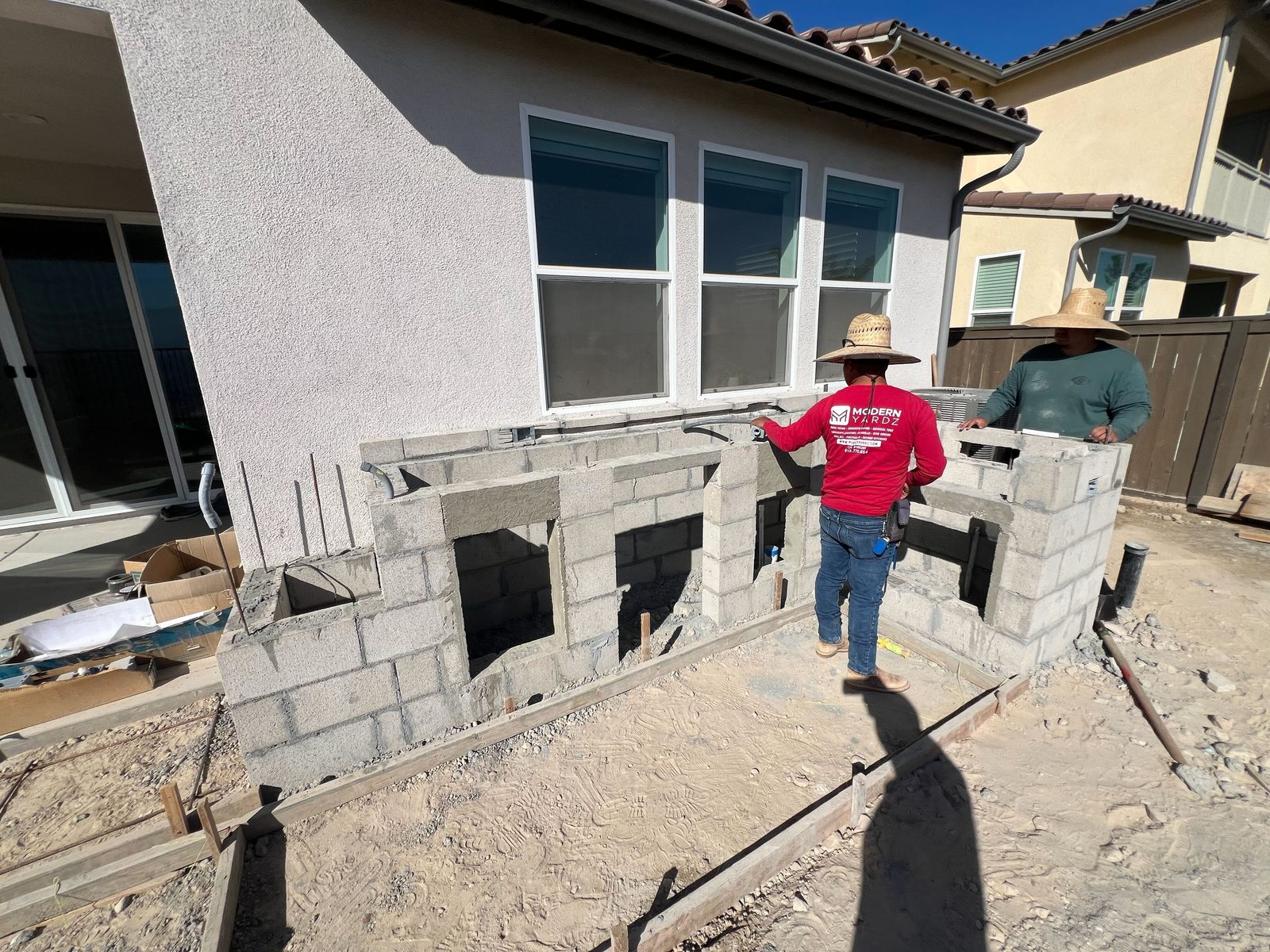 Abshire Brothers Lawn & Landscape masons building the block base of a custom outdoor kitchen in Rayne