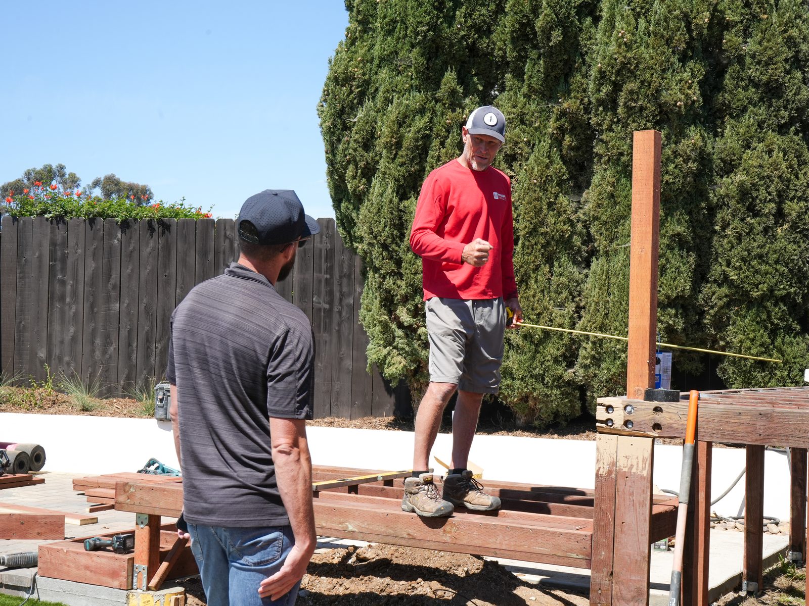 Abshire Brothers Lawn & Landscape carpenters measuring and laying out pergola framing in a Rayne backyard