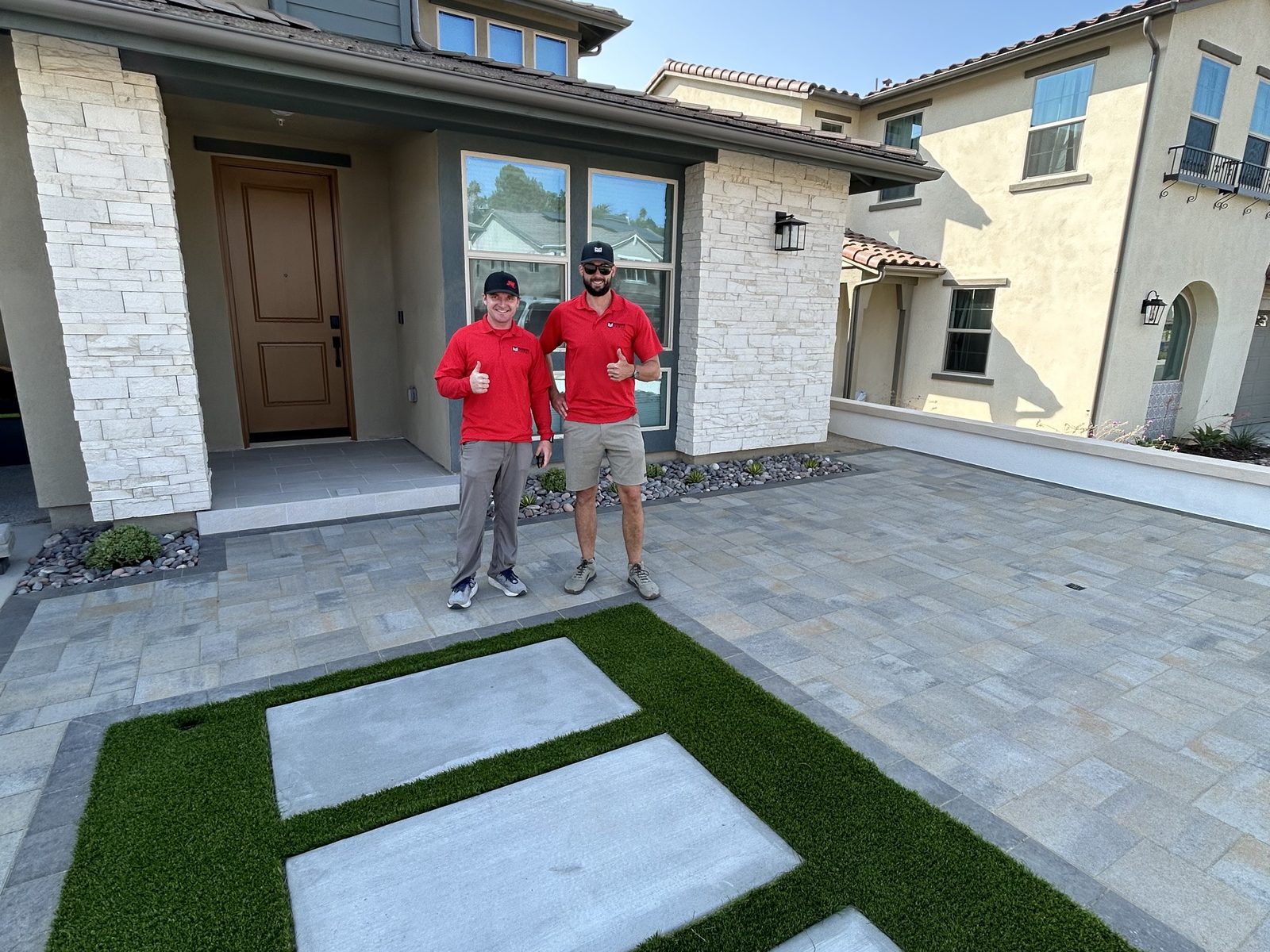 Abshire Brothers Lawn & Landscape crew at a completed paver driveway with artificial turf inlay in Rayne